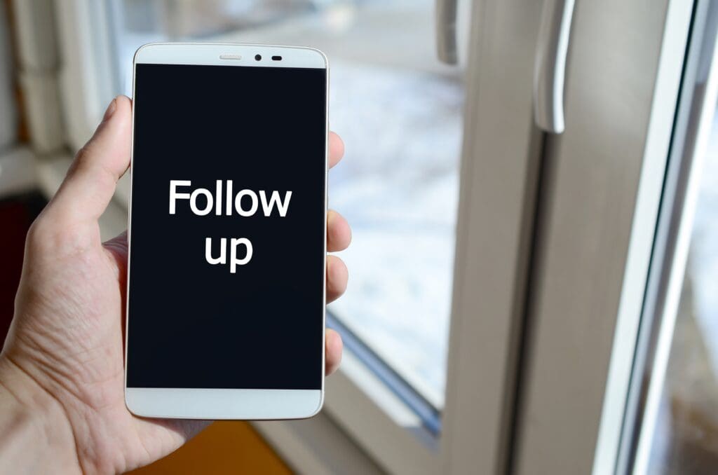 A person sees a white inscription on a black smartphone display - Real-Estate-Leads Expert Tips for Your First 30 Days as a Real Estate Agent: Concept of following up