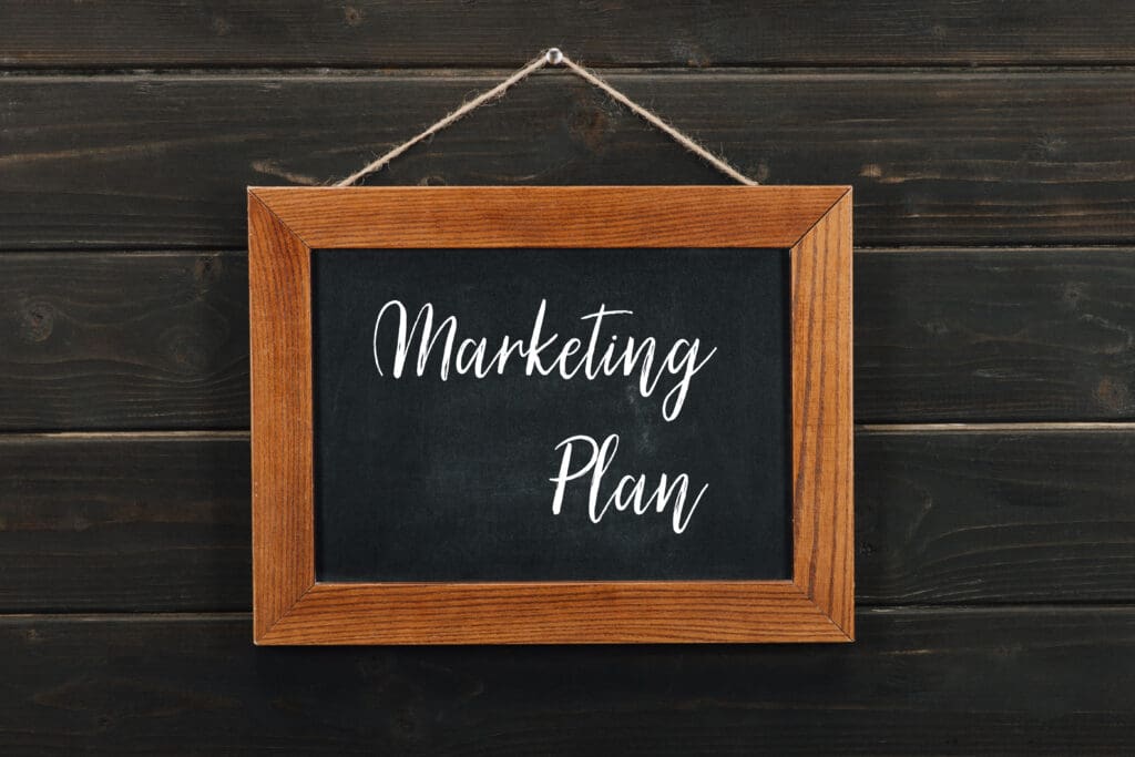 Board with lettering marketing plan hanging on wooden wall - Real-Estate-Leads How to Succeed as a New Real Estate Agent: Building a marketing plan