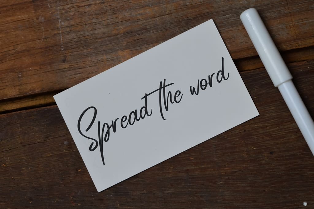 Top view of pen and memo note written with text SPREAD THE WORD - Real-Estate-Leads How to Develop a Robust Referral Program in Real Estate: Identify Your Sources