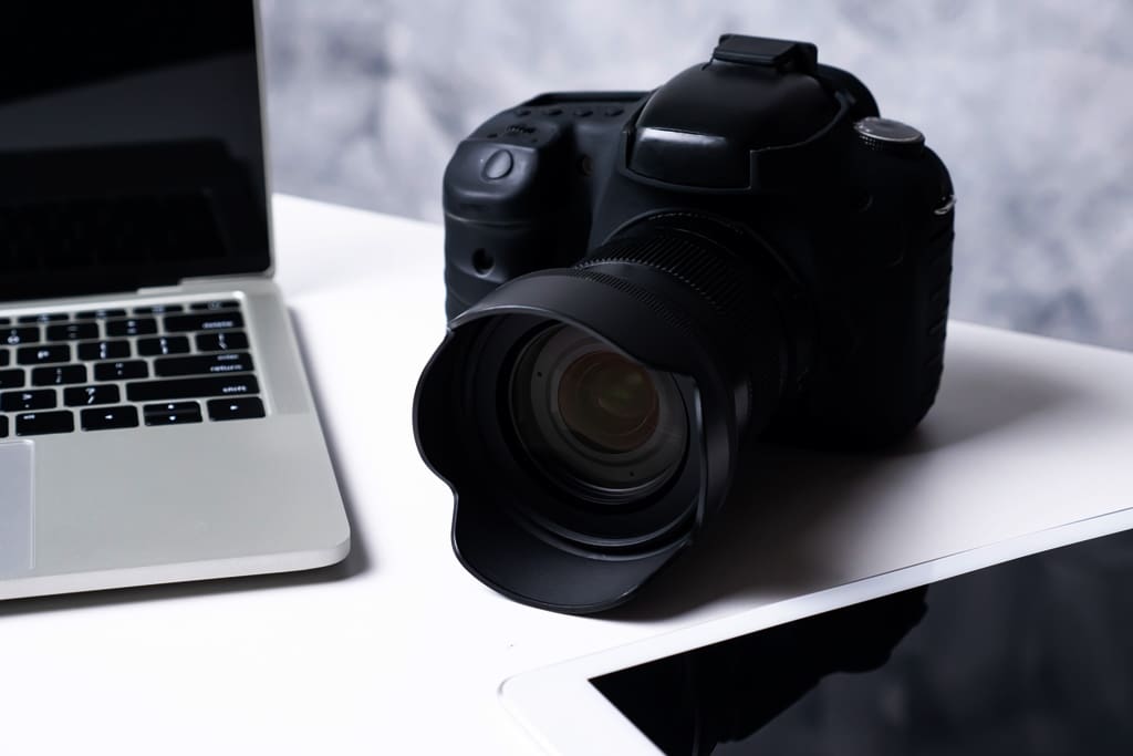 A black digital camera a tablet and a computer laptop on a table - Real-Estate-Leads Optimizing Your Real Estate Listings for Maximum Offers: Photography and Virtual Tours