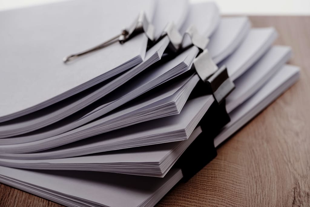 close up view of stacks of blank paper with metal binder clips - Real-Estate-Leads How to Address Tenant-Landlord Disputes When Managing Property: Documentation