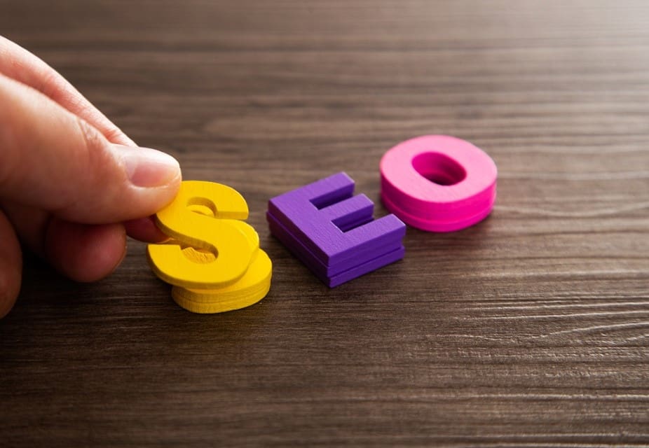 Hand arrange wood letters as SEO abbreviation - Real-Estate-Leads How to Host Educational Real Estate Webinars for Your Clients: SEO